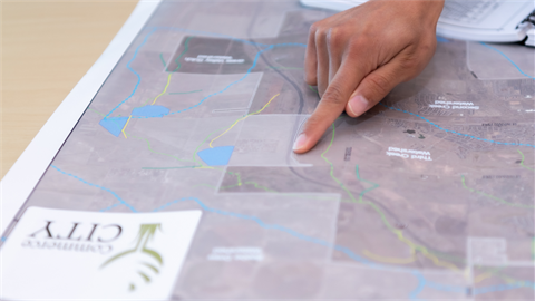 Someone points at a paper map of Commerce City