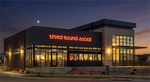 Restaurant with lights on, in sunset, with name: Third Round Social. 