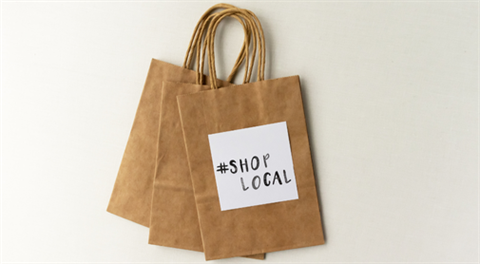 Sign on paper shopping bag says Shop Local