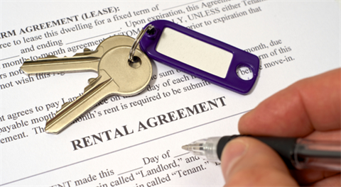 Person signing a rental agreement. Keys sit on the document.