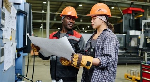 Two workers looking at a big piece of paper. 