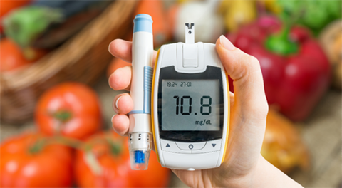 Person holds diabetes monitor over vegetables