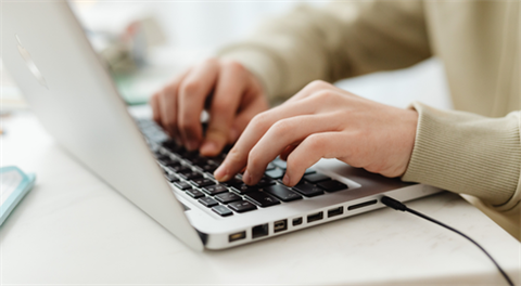 A person types on a laptop