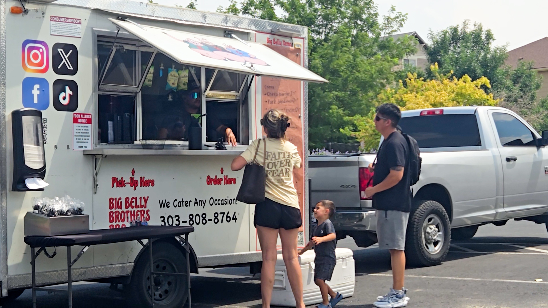 Two people standing at a food truck. 