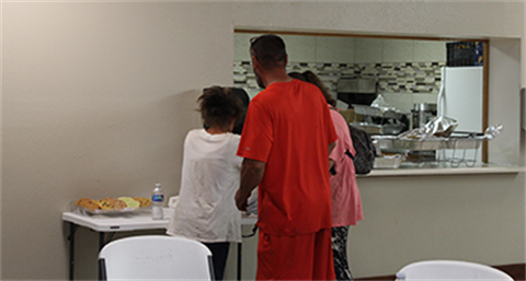 People standing in a room near a wall cut-out. 