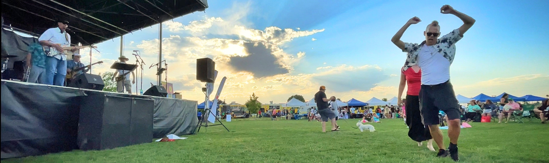 People dancing to a band playing at a park. 