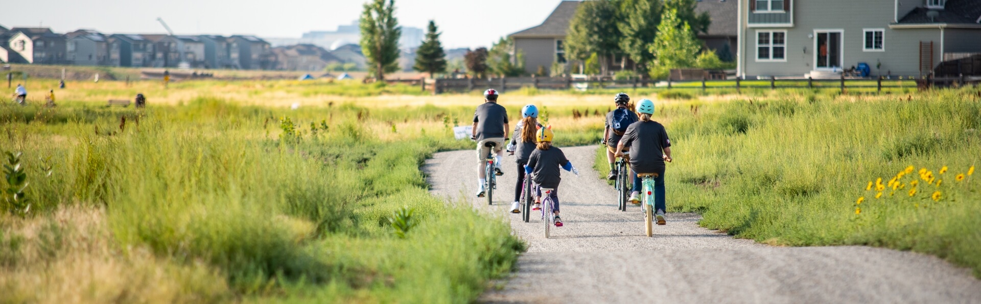 a family rides bikes on a path with neighborhood homes in the background