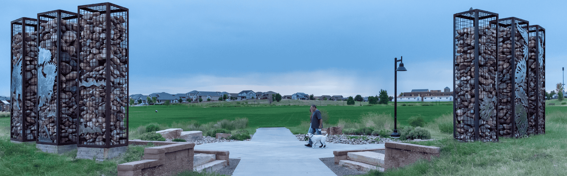 Residents walk their dog on the path in front of the public art installation at Fronterra Park